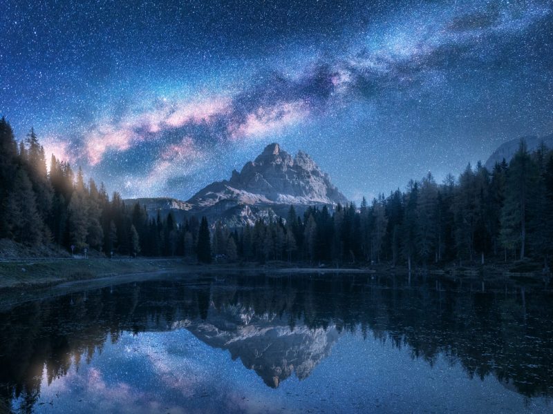 Milky Way over Antorno lake at night. Summer landscape with alpi Milky Way over Antorno lake at night. Summer landscape with alpine mountains, trees, blue sky with milky way and stars, beautiful reflection in water, high rocks. Dolomites, Italy. Space and nature